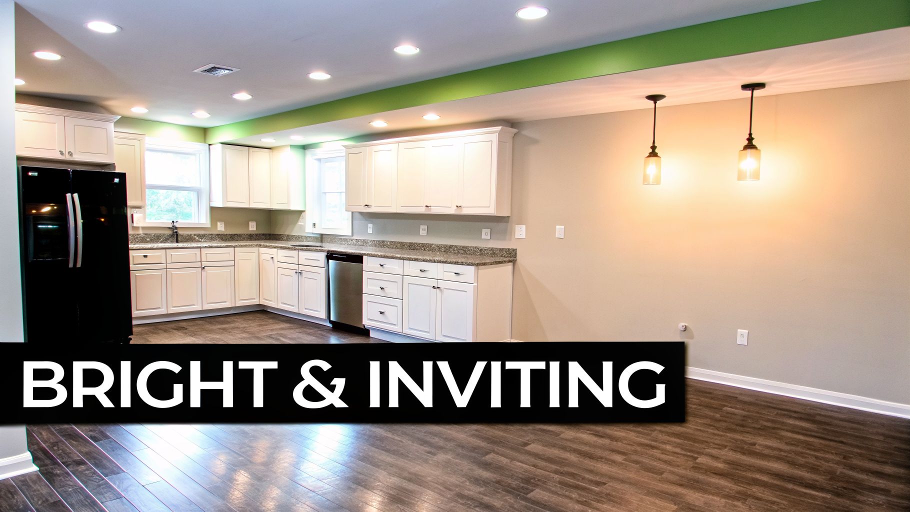 A bright, modern basement kitchen featuring white cabinets, dark wood flooring, and pendant lights.