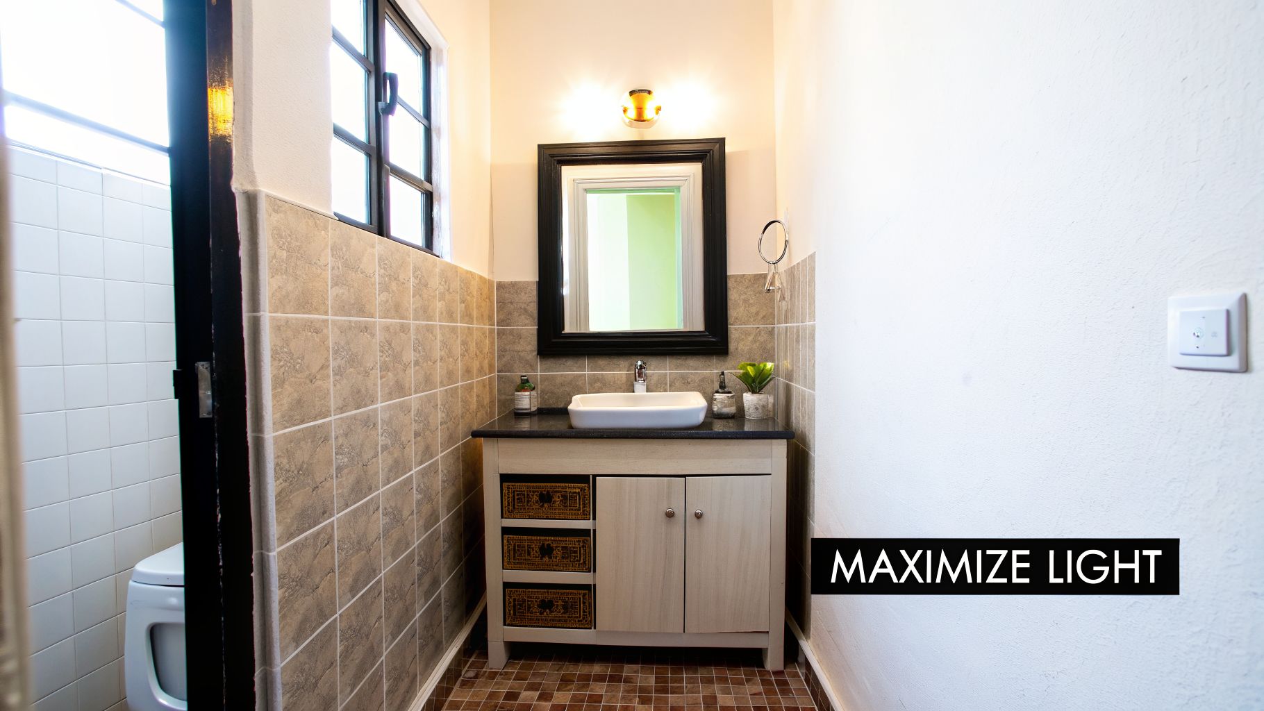 Bright small bathroom featuring a light vanity, vessel sink, framed mirror, and tiled walls.