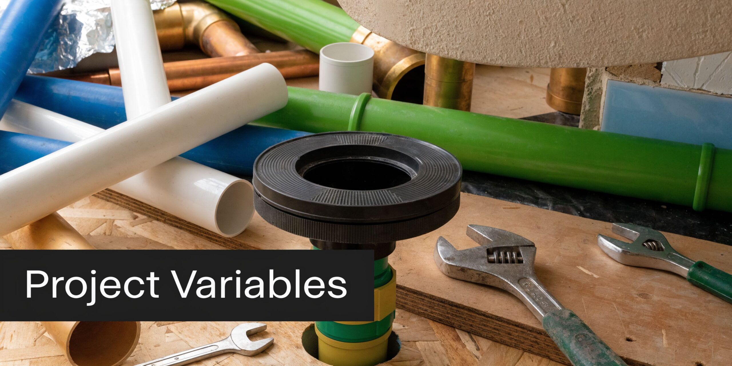 A collection of various plumbing pipes, toilet fittings, and adjustable wrenches on a wooden construction surface.