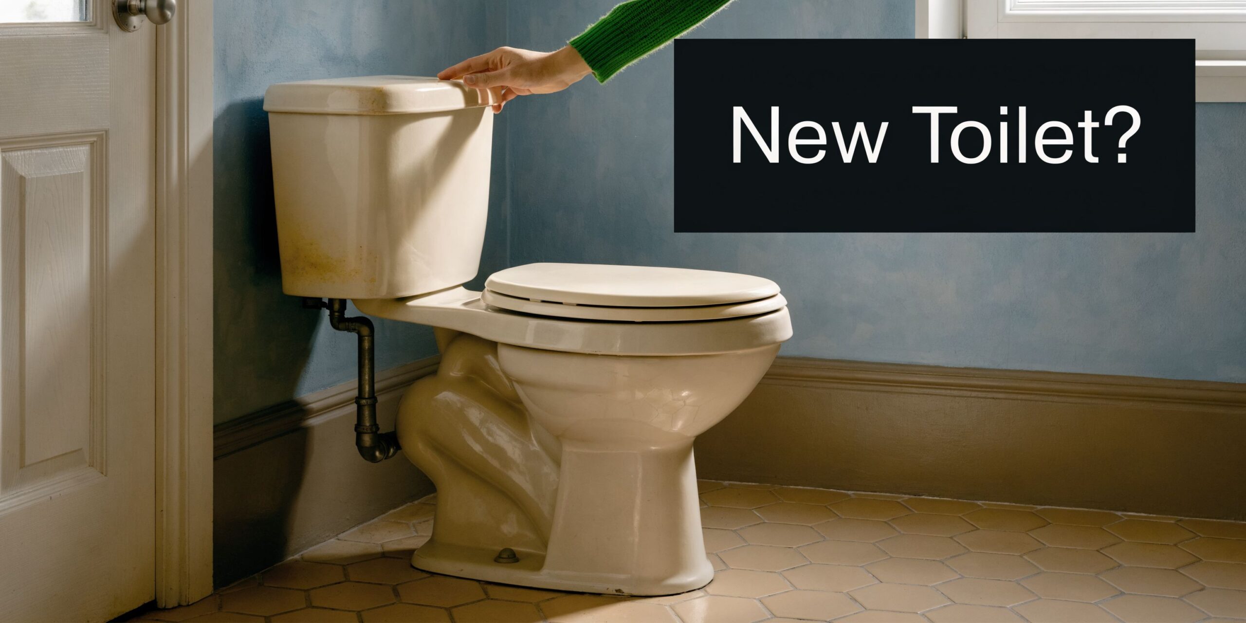 A person in a green sweater pressing the flush button on a vintage off-white bathroom toilet.