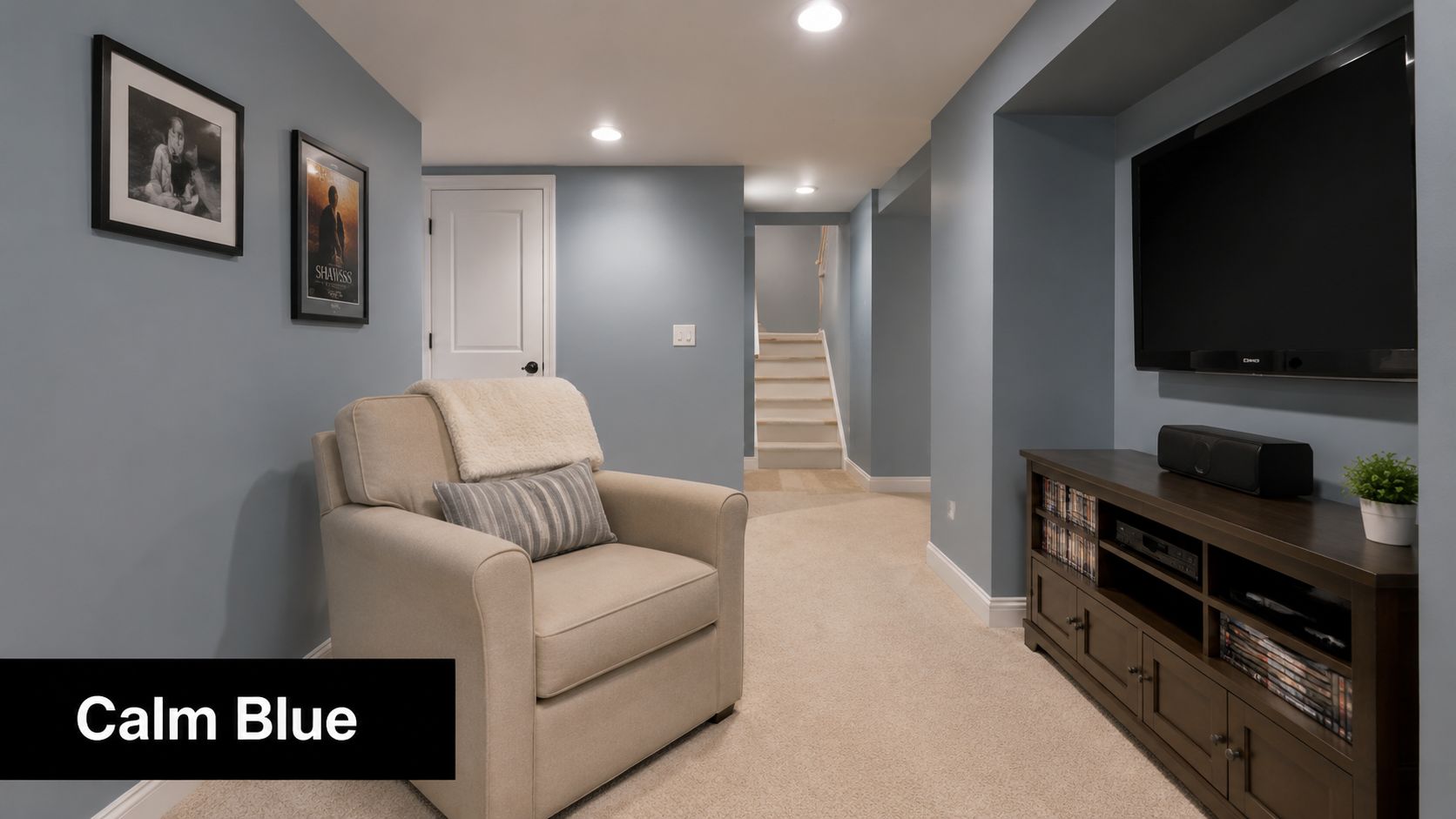 A cozy basement living area featuring calm blue walls, a beige armchair, and a dark wooden media console.