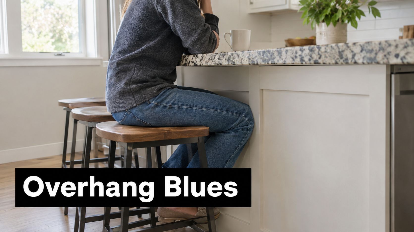 A person sitting on a bar stool at a kitchen island countertop with an inadequate overhang.